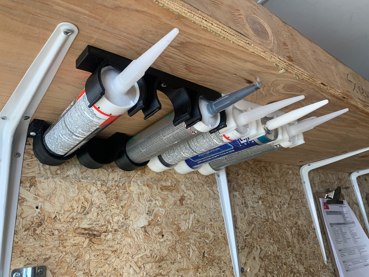 Caulk tube holder under shelf